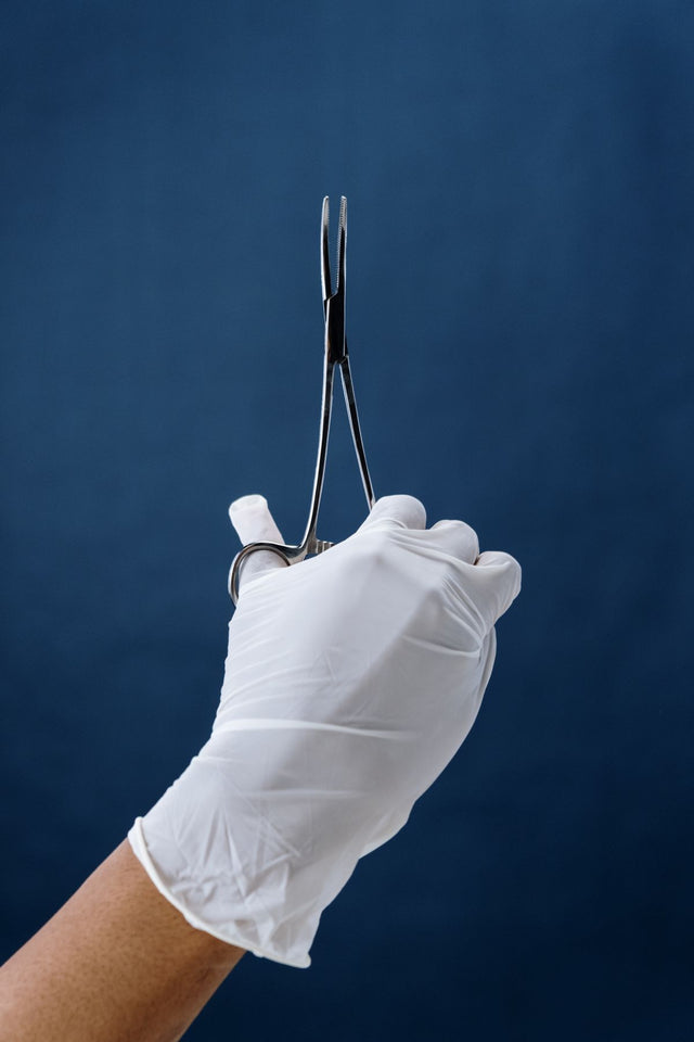 Gloved hand holding surgical forceps